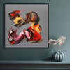Vibrant abstract painting displayed in a contemporary interior setting. Bold brushstrokes in fiery shades of red, orange, and yellow create a dynamic, expressive composition. The artwork serves as a focal point, complemented by the minimalist vase and floral arrangement on the nearby shelf. This captivating abstract artwork would make a striking addition to any modern home or office space.