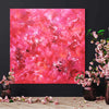 Vibrant abstract painting featuring swirls of pink and red hues, surrounded by vases of delicate pink flowers on a wooden surface