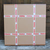 Large fragile cardboard boxes stacked on a wooden floor, surrounded by red "FRAGILE" warning tape