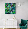 Vibrant abstract painting in green and blue hues displayed on the wall above a white dresser. Plush green armchair and modern white pendant light in the contemporary interior setting.