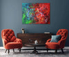 Red Green Abstraction | Summer Bloom 36x48" - Vibrant abstract artwork with bold red, green, and multicolored strokes on a canvas, displayed in a modern living room setting with dark furniture and accent pieces.
