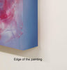 Vivid abstract landscape painting with vibrant pink and blue tones, displayed on a white surface.