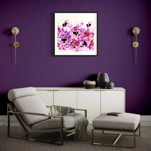 "Spring Blossom" Signed Edition Art Print - Vibrant abstract artwork in pink and purple hues, framed and displayed on a bold purple wall in a modern living room setting with neutral-toned furniture.