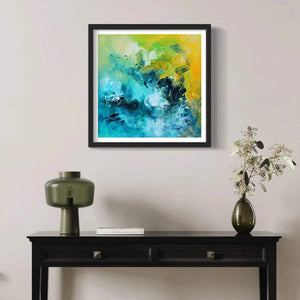 Vibrant abstract art print "Spring Morning" by Paresh Nrshinga displayed on a wall above a dark wooden table with decor items.