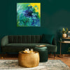 Modern Abstract Art | April Showers 100x100cm
Large abstract square painting with vibrant blue, green, and yellow brush strokes displayed on a dark green wall above a green velvet sofa and gold accent table in a cozy living room setting.