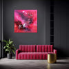 Large vibrant abstract canvas art titled "Fuchsia Heaven" displayed on a dark gray wall in a modern interior setting. The artwork features bold brushstrokes in shades of pink, red, and white. A plush pink sofa and a round gold side table complement the artwork's earthy color scheme, creating a stylish and contemporary living space.